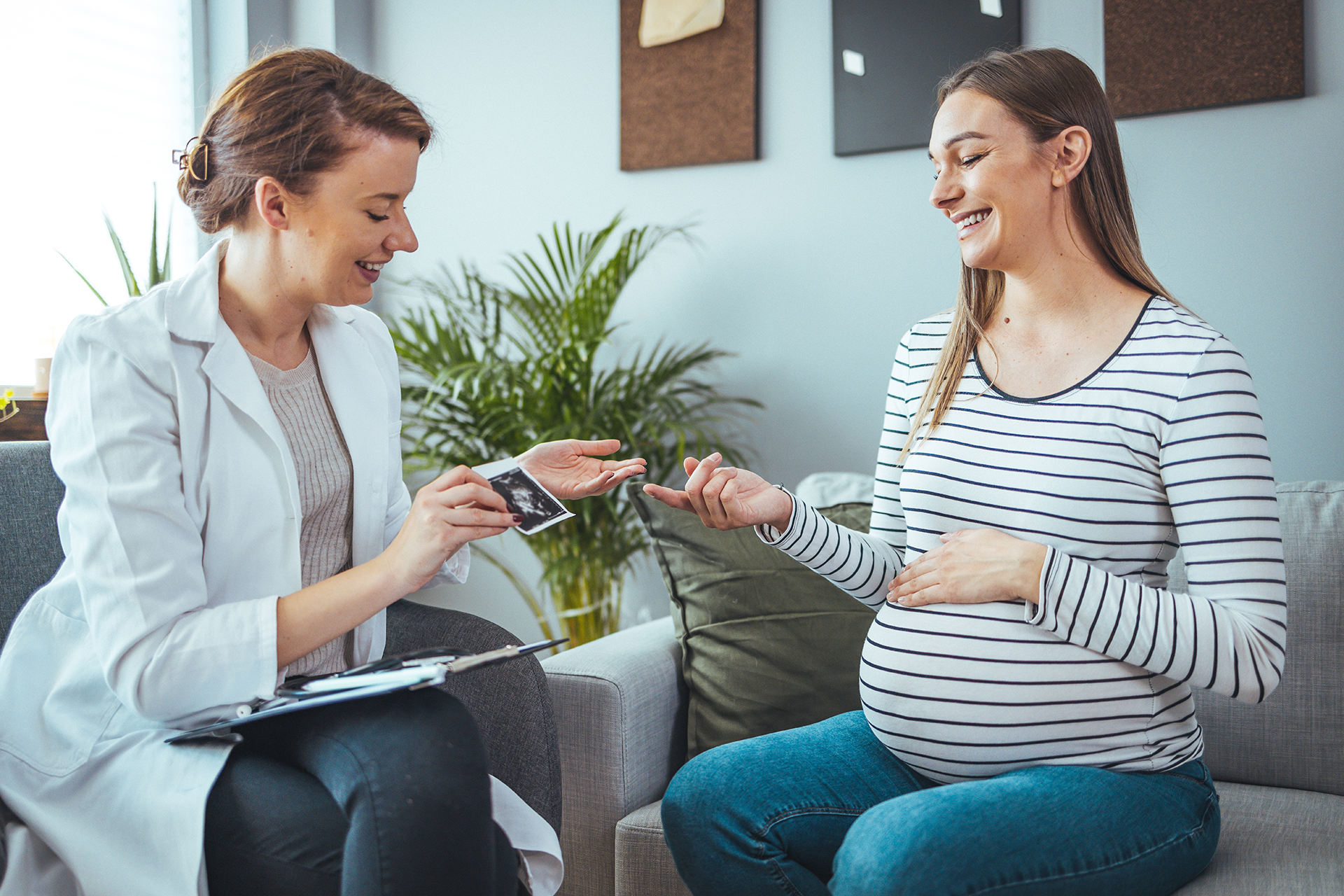 Hebamme zeigt schwangeren Frau ein Ultraschallbild